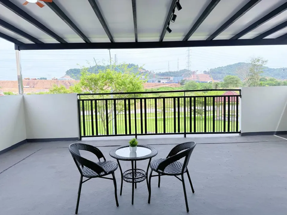 Private balcony with a rattan bistro table and two chairs overlooking a lush hillside view
